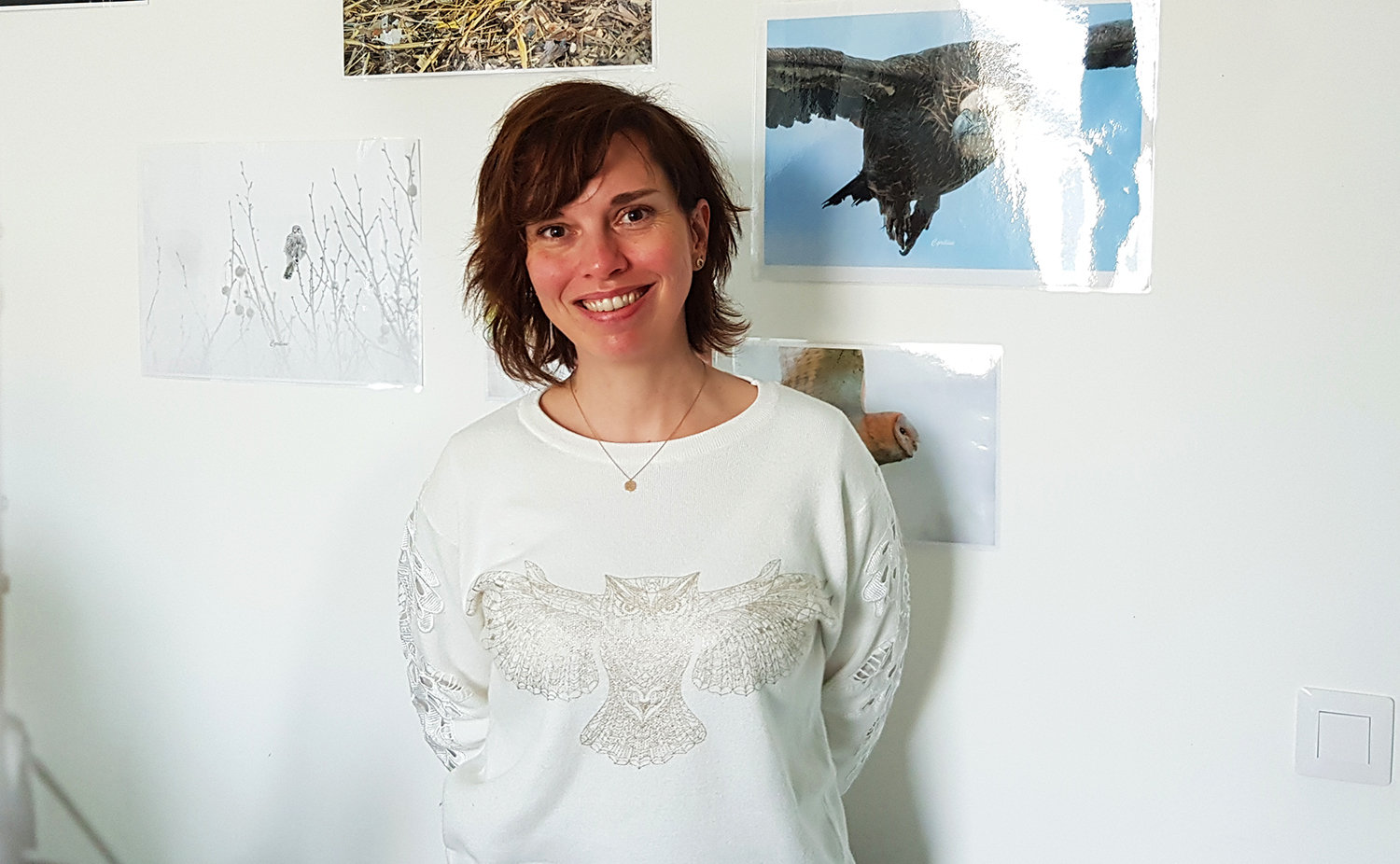 Portrait de Céline GRISOT prise devant quelques-unes de ses propres photos. La directrice de l’association est photographe amatrice à ses heures. La faune sauvage est évidemment son sujet de prédilection © Globe Reporters