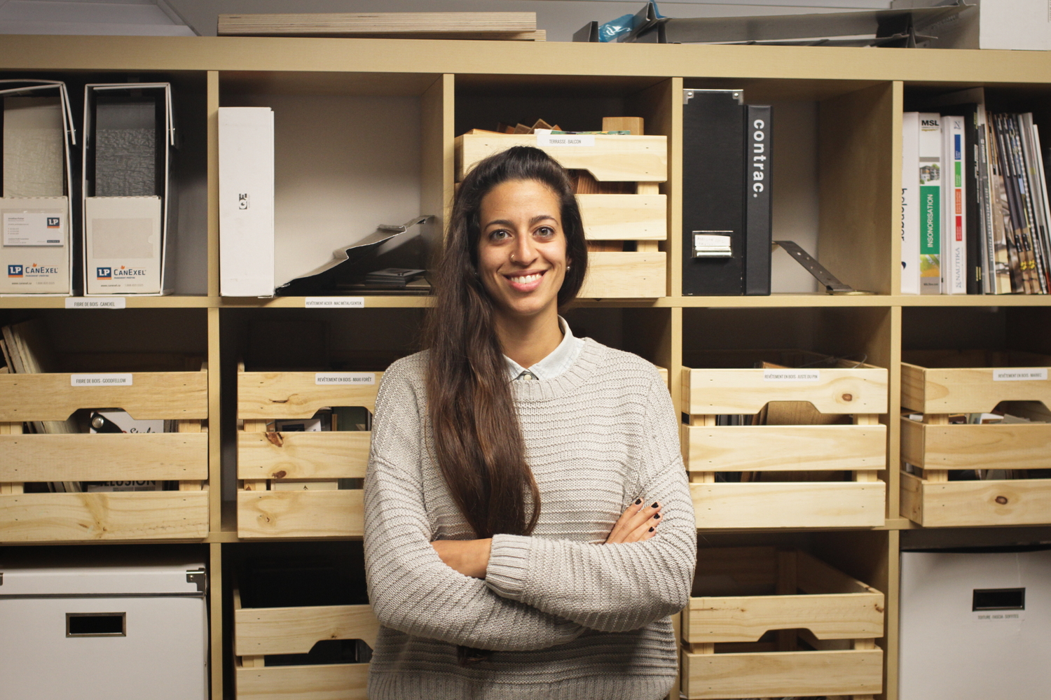 Elita MAALOUF dans la salle de réunion, devant des caisses de matériaux écologiques.