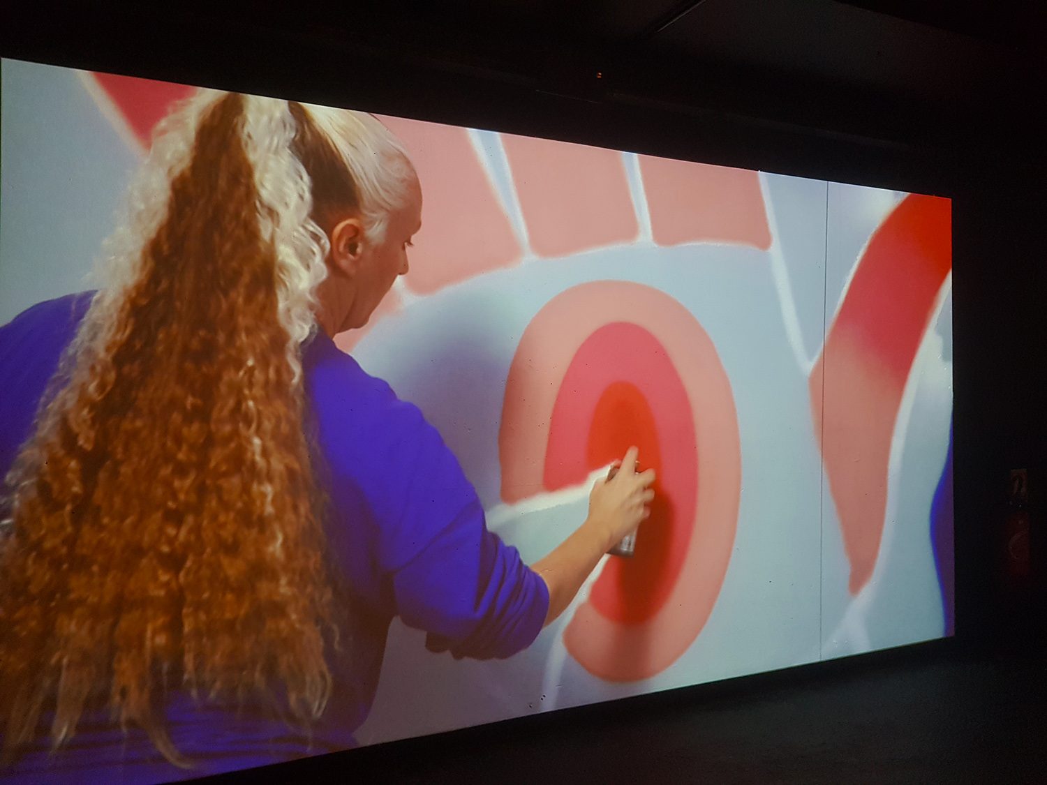 Lors de l’exposition « Loading, l’art urbain à l’ère du numérique », on retrouve plusieurs travaux de KASHINK, que l’on voit ici, dans une vidéo, en train de peindre sur un mur © Globe Reporters