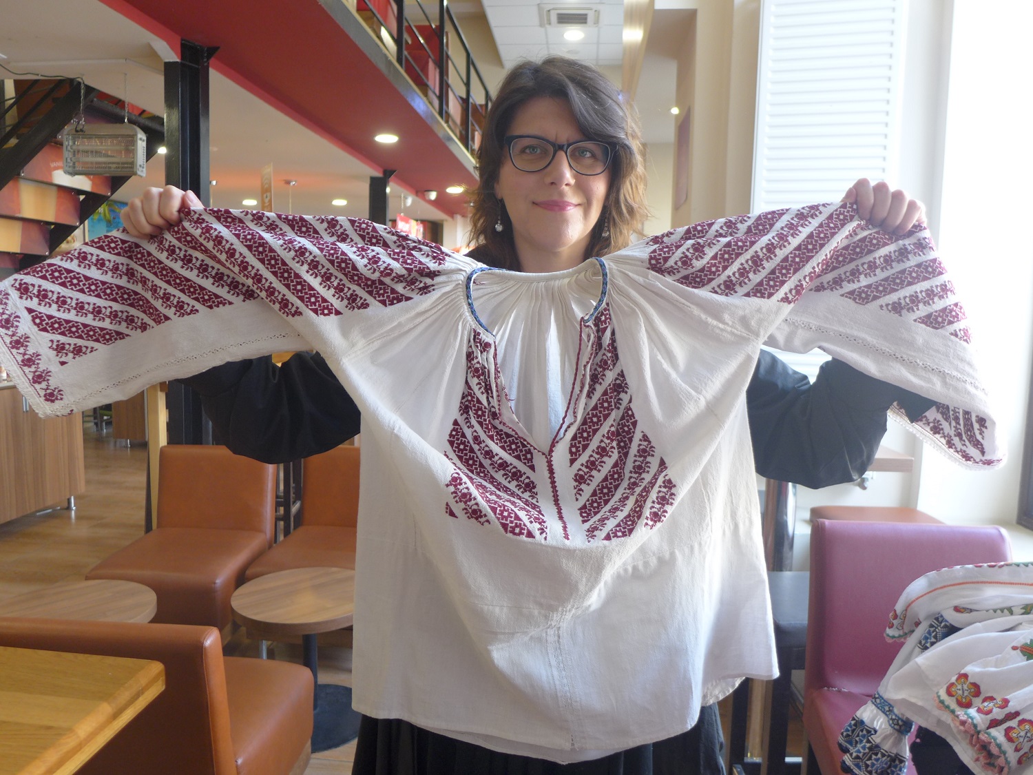 Andreea TANASESCU déploie une blouse roumaine : lorsqu’on lève les bras, on dirait des ailes.