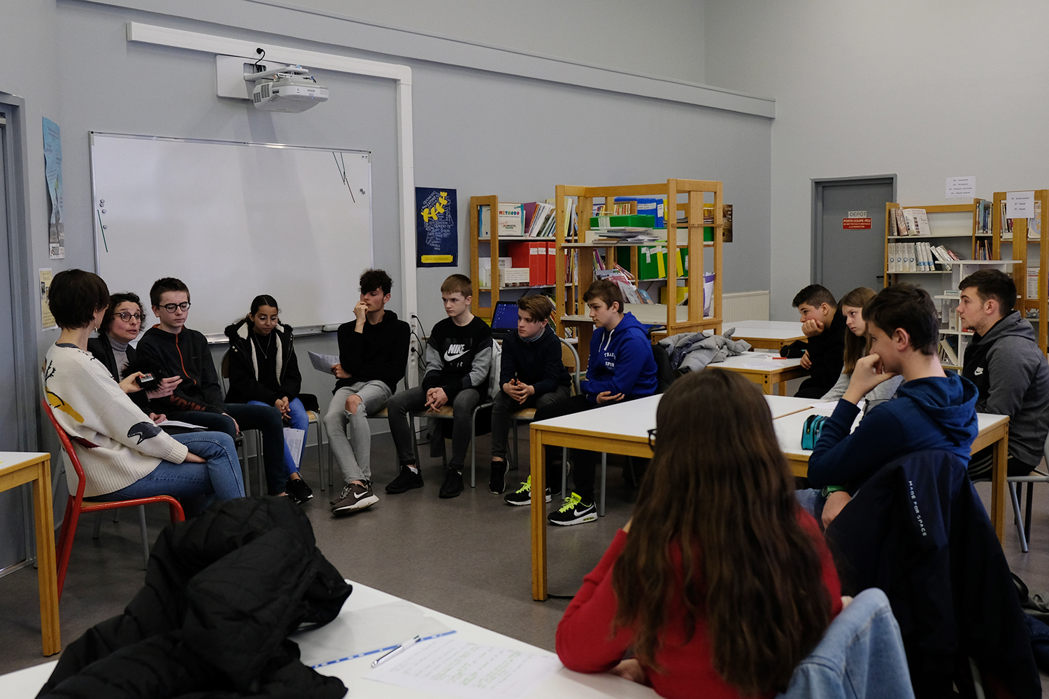 Les élèves interrogent la chercheuse devant les autres collégiens de leur classe, tous très attentifs face à l’exercice.