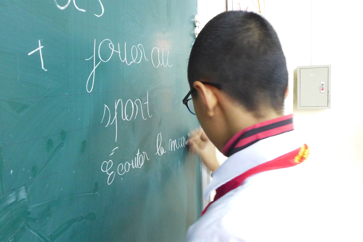 Un élève décrit ses loisirs, en français, au tableau. Les professeurs incitent les élèves à prendre la parole dans les langues étrangères pour mieux les apprendre.