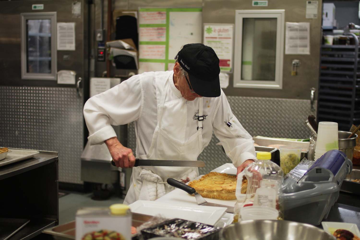 Un cuisinier en pleine préparation. Il coupe un pâté à la viande, une recette typiquement québécoise.