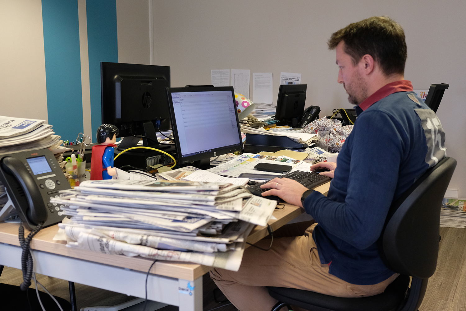 Les journalistes travaillent dans un espace partagé, mais ils ont chacun leur bureau. Tous les matins, ils reçoivent et lisent les éditions du jour de la locale et des locales voisines, d’où la pile au premier plan. 