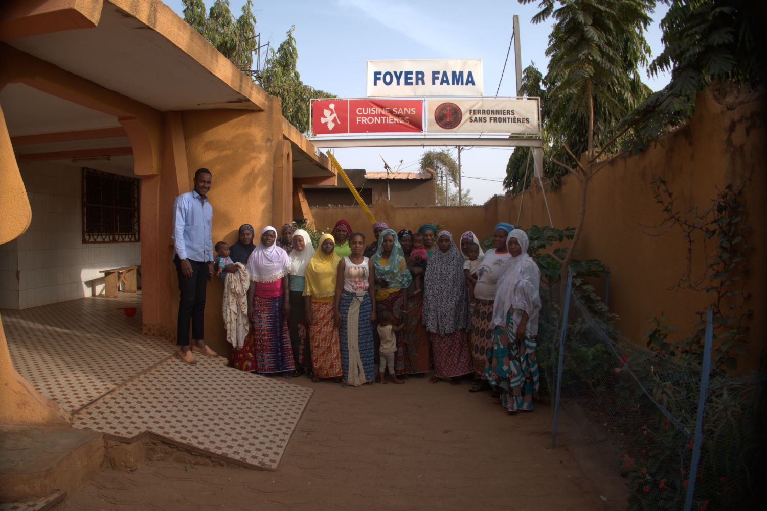 Dans la cour du Foyer FAMA, les femmes qui habitent et qui se forment pour être des petites commerçantes et pouvoir maintenir leurs enfants. Mohamed est le logisticien du foyer. C’est aussi lui qui joue avec les enfants © Globe Reporters