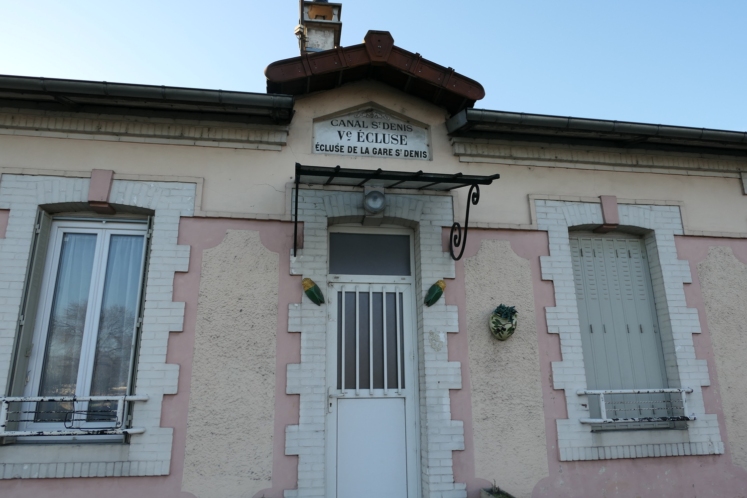 L’éclusier a une petite maison rose pâle sur l’une des berges du canal Saint-Denis. Les bateaux nettoyeurs sont amarrés juste devant © Globe Reporters