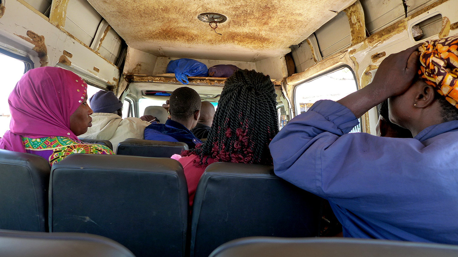 Après avoir quitté la route nationale et le grand bus, l’envoyée spéciale monte à l’arrière du taxi collectif qui dessert les petits villages de la route secondaire © Globe Reporters