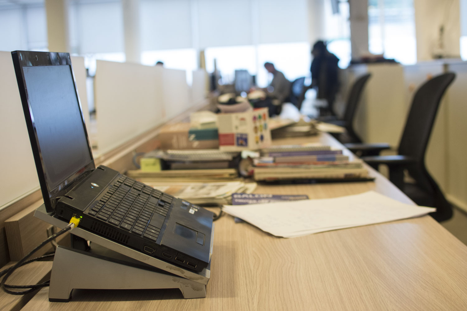 Un ordinateur et des piles de journaux : la base d’un bureau de journaliste de presse écrite © Globe Reporters