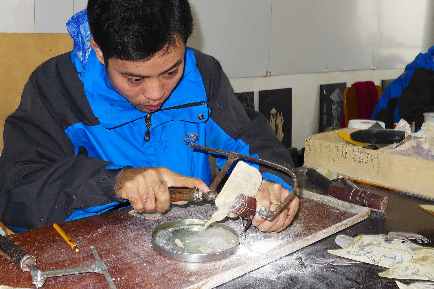 Cet artisan découpe des morceaux de nacre pour les coller sur les tableaux.