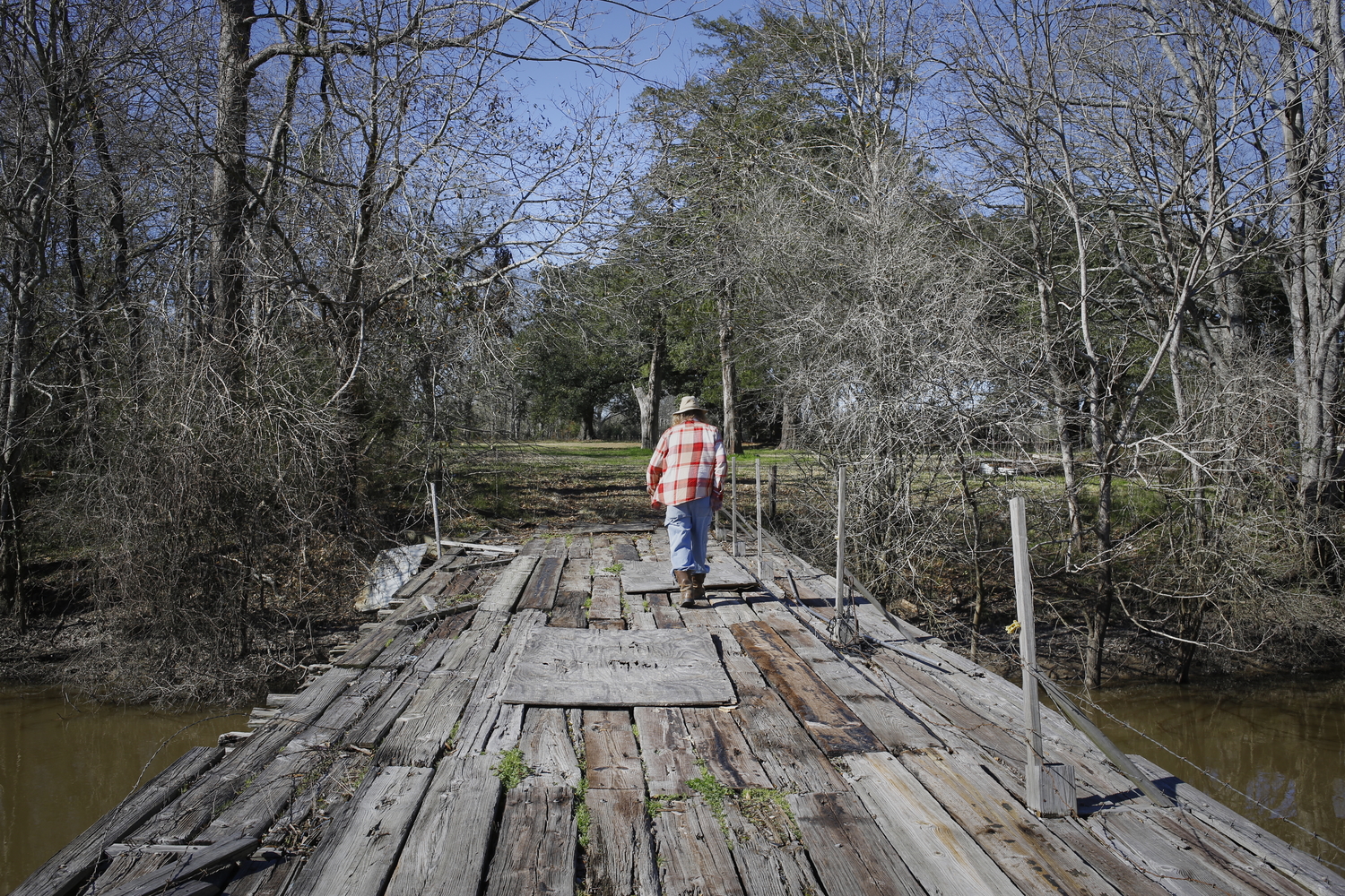 Bobby traverse un pont qui l’emmène à son terrain près de bayou Bourbeux © Globe Reporters