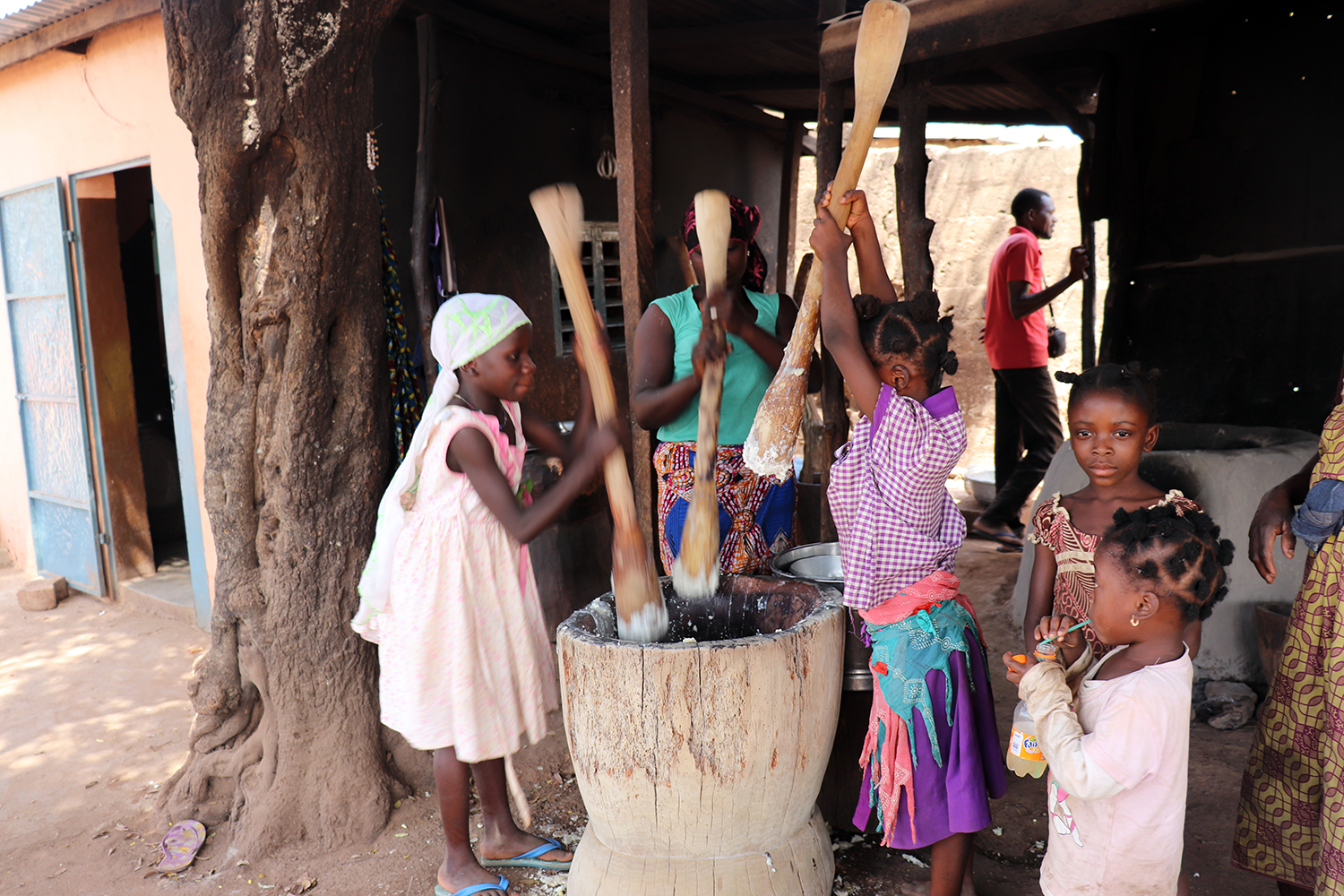 Devant un restaurant dans la ville de Natitingou, dans le nord du pays, des femmes et des jeunes filles en vacances pilent l’igname. 