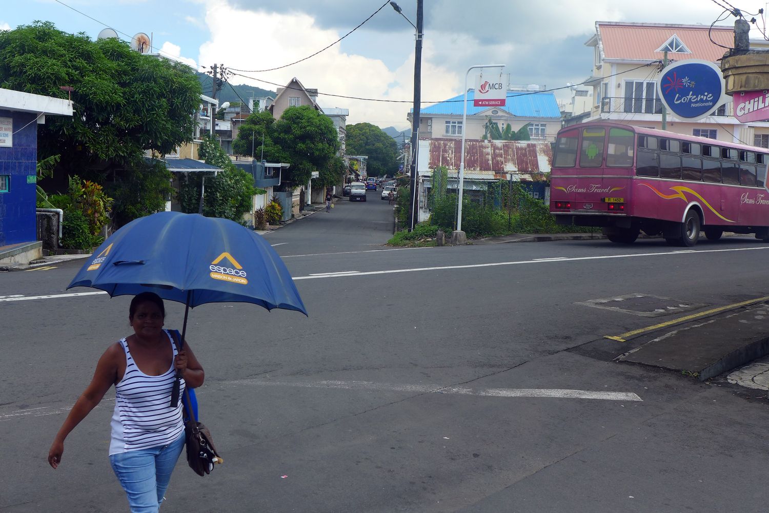 Le long trajet lui permet de saisir des instants de vie de sa nouvelle destination. Les rues sont vivantes. Les Mauriciens ont l’air de circuler beaucoup à vélo et à pied. Ils sont aussi nombreux à marcher dans la rue avec des parapluies pour se protéger du soleil… et des « pluies vagabondes », l’expression mauricienne pour parler des averses régulières durant la journée. Comme à La Réunion, les habitants de l’île expliquent à Sidonie que c’est la première année qu’il pleut autant !