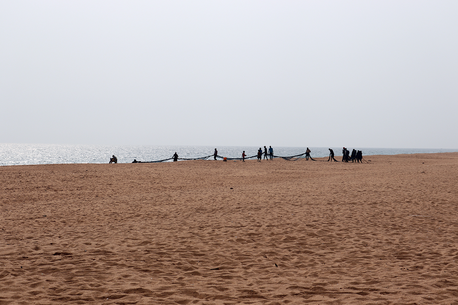 Des jeunes pêcheurs se préparent pour tirer une extrémité du filet depuis la plage. 