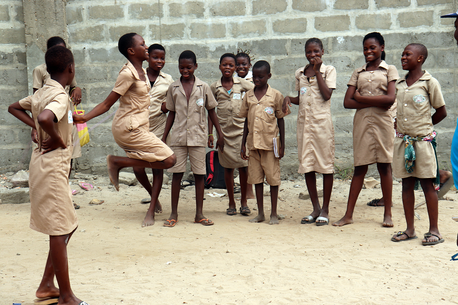 Des filles et des garçons jouent à tour de rôle à la corde pendant la récréation. 