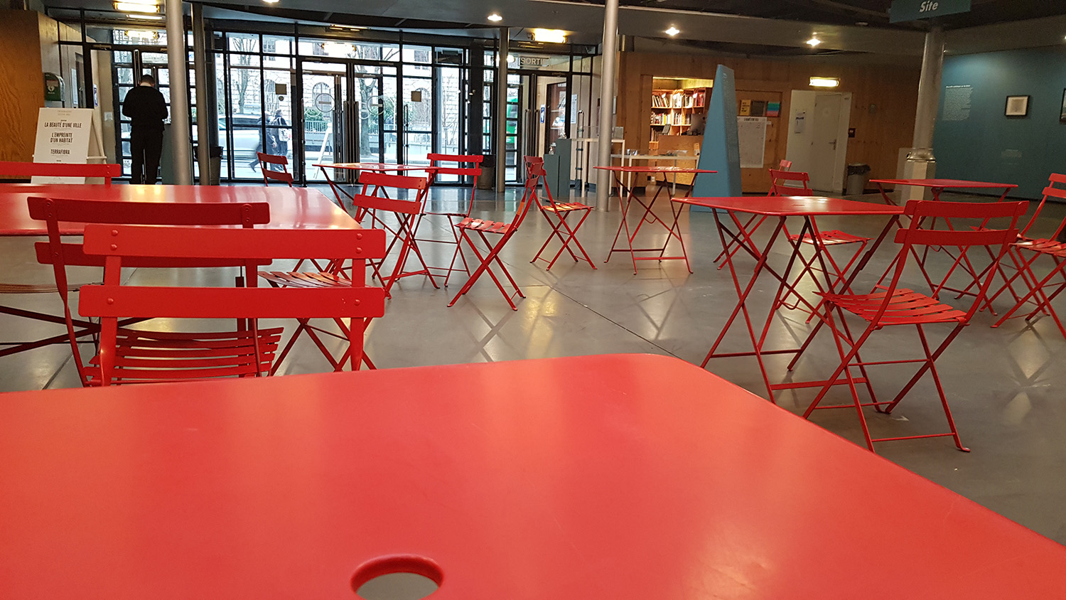 L’heure tourne, c’est l’heure de s’installer et d’attendre Fanny TASSEL. Pour réaliser l’interview, Chloé et l’architecte s’installent au centre du lieu d’exposition, sur les tables rouges. L’endroit est complètement libre d’accès, et il n’y a pas besoin de demander une autorisation. « On peut même amener son pique-nique », nous assure Fanny TASSEL ! © Globe Reporters