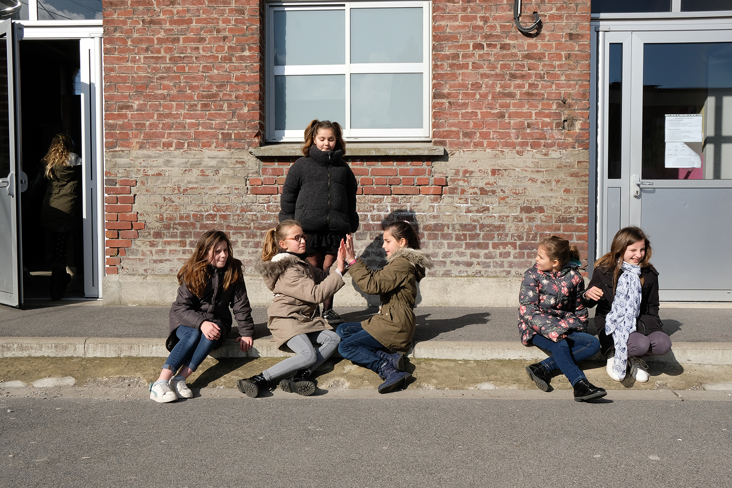 A l’heure de la récréation, les dessins prennent vie : les filles discutent et jouent sur le côté.