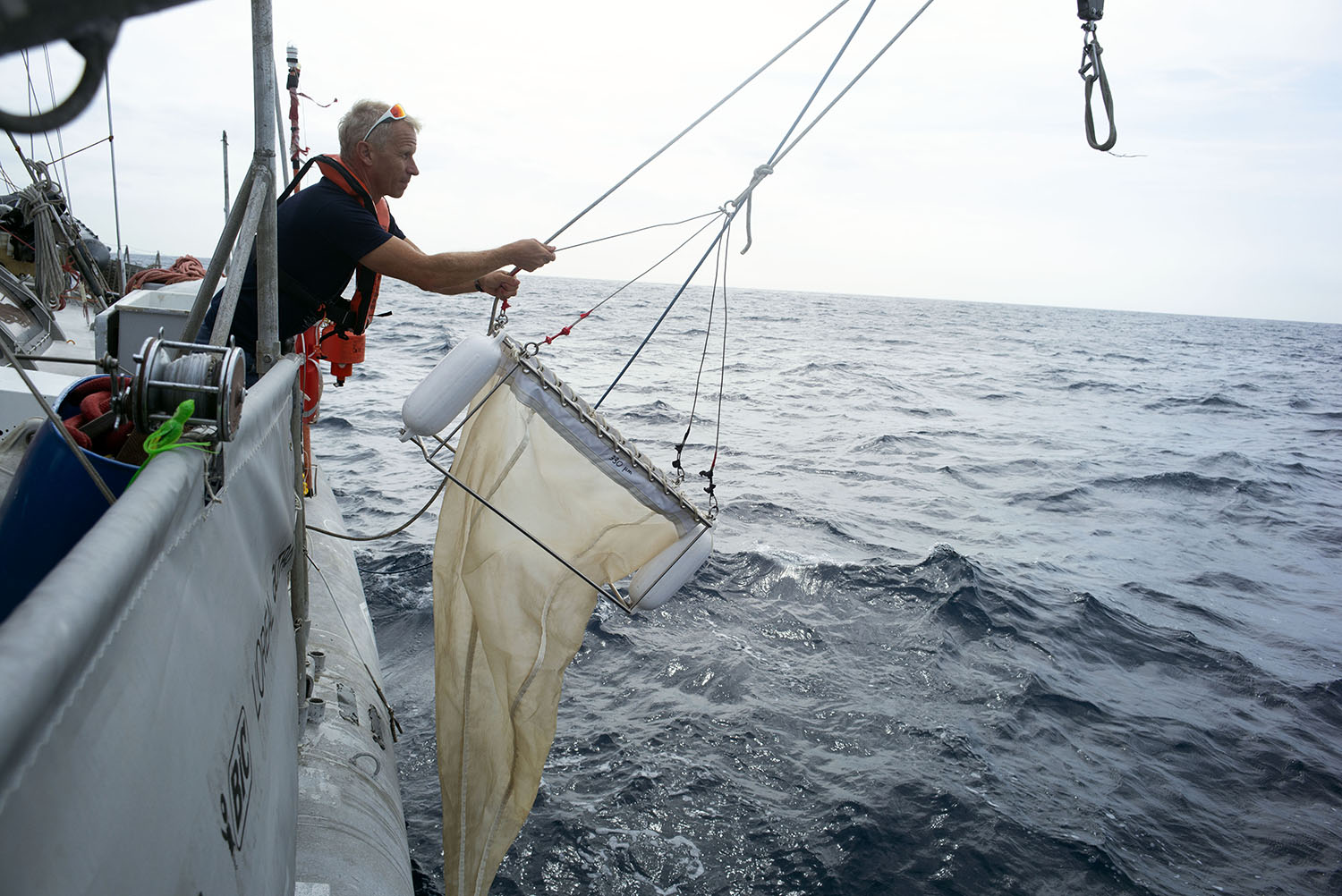 Jean-François GHIGLIONE en train d’utiliser un autre outil de prélèvement, le filet manta. Ce petit filet plonge en moyenne cinq à six fois par jour dans les eaux traversées par la goélette. Il est très efficace pour récolter le plastique flottant et les micro-organismes de surface © Samuel Bollendorff