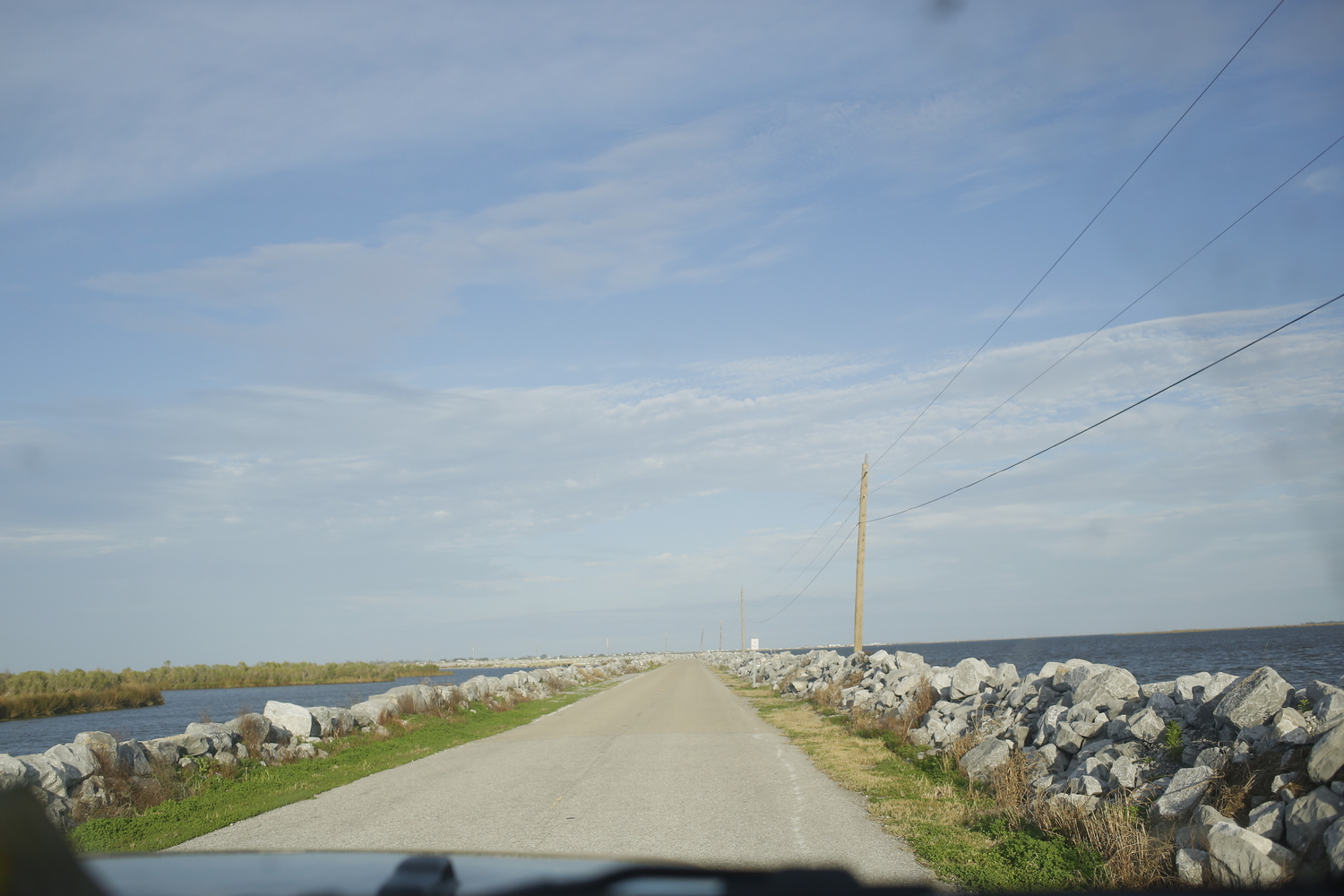 La route vers l’Isle Jean-Charles est entourée par l’eau, ce qui n’était pas le cas il y a une dizaine d’années. Des pierres ont été installées pour empêcher les inondations sur la route © Globe Reporters