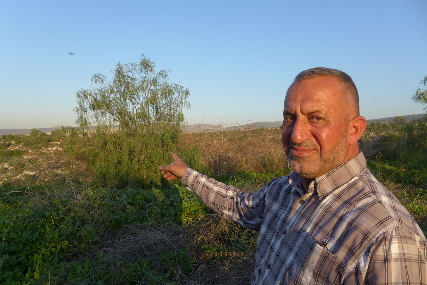 Ahmad qui montre où se trouve la parcelle pour les cultures biologiques © Globe Reporters