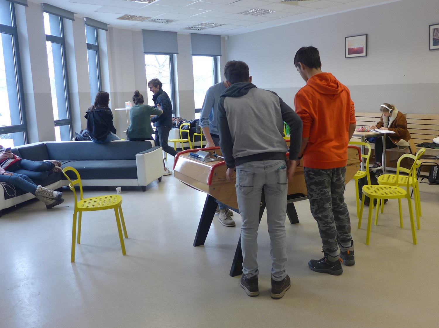 Le foyer, avec un baby-foot, des canapés et des bancs.