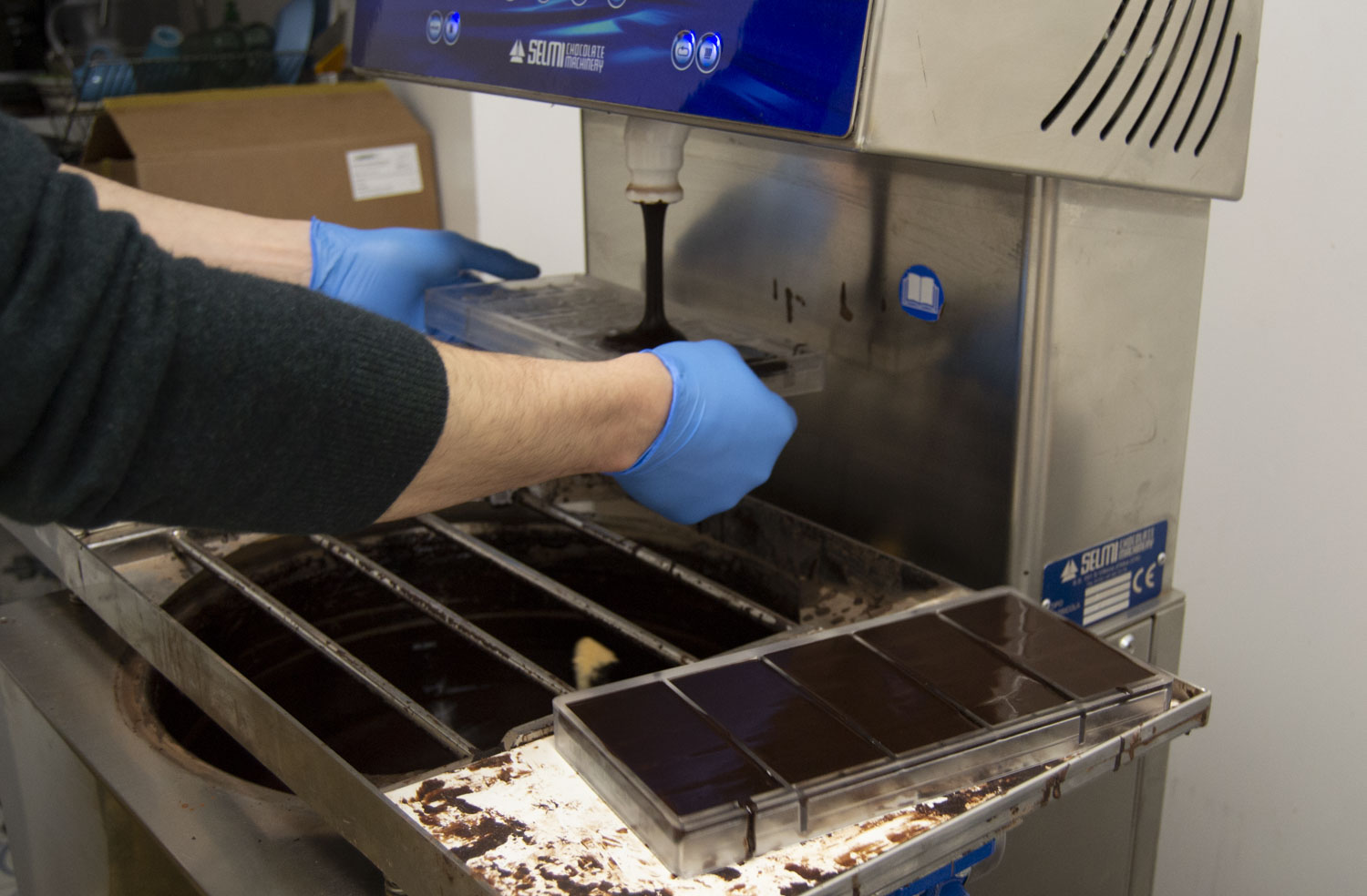 Damien coule le chocolat de la tempéreuse dans des moules © Globe Reporters