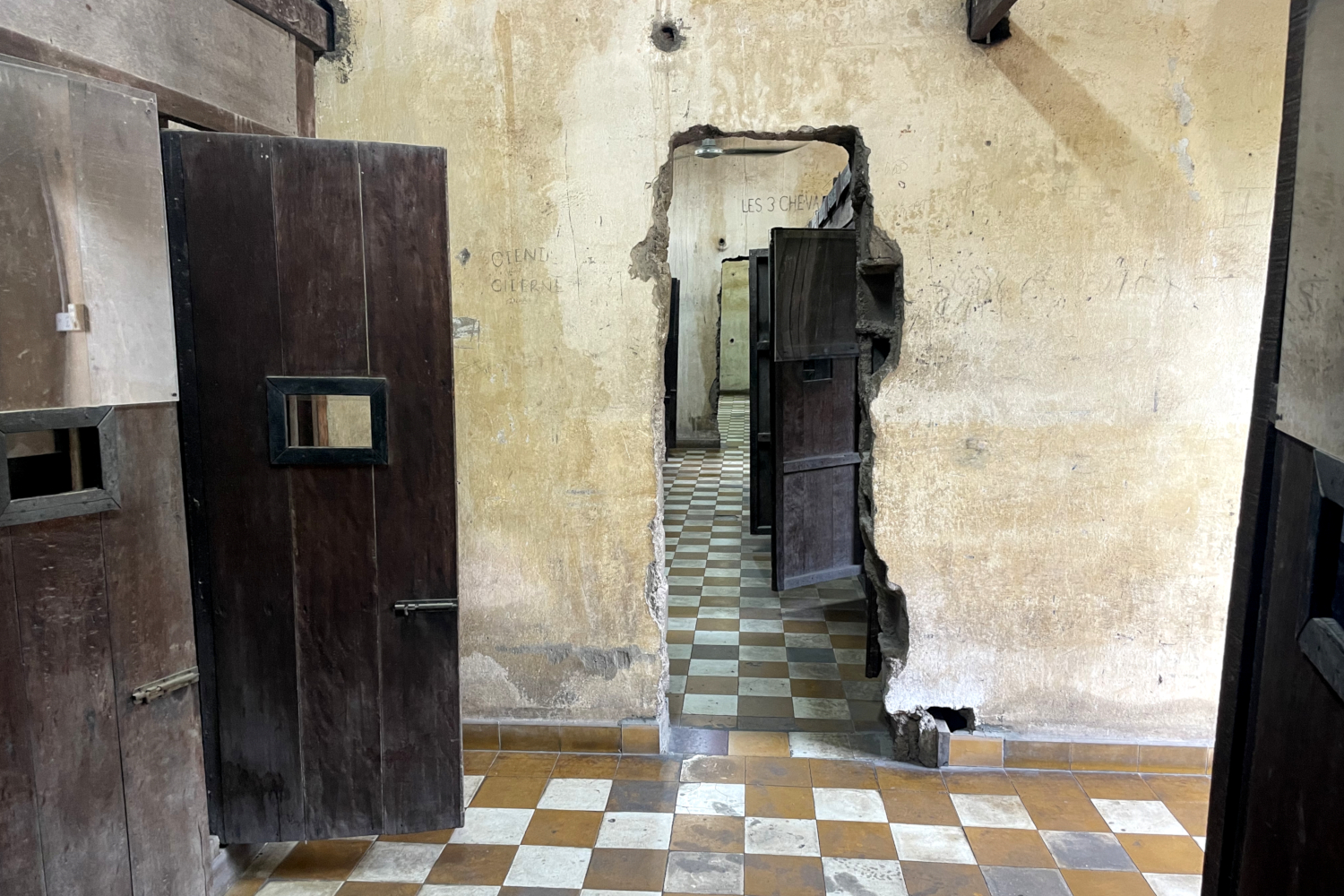 Cellules individuelles en bois construites à l’intérieur des anciennes salles de classe de la prison de Tuol Sleng (S21). Le mur a été percé entre les salles de classe transformées en prison © Globe Reporters