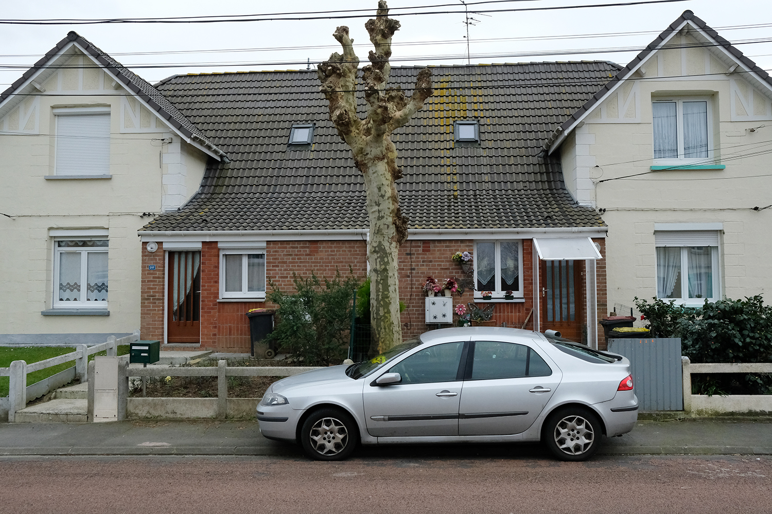 Ici la maison est divisée en quatre logements : deux de chaque côté (façades beiges avec faux colombages) et deux au centre, plus petits, avec la façade en briques. 