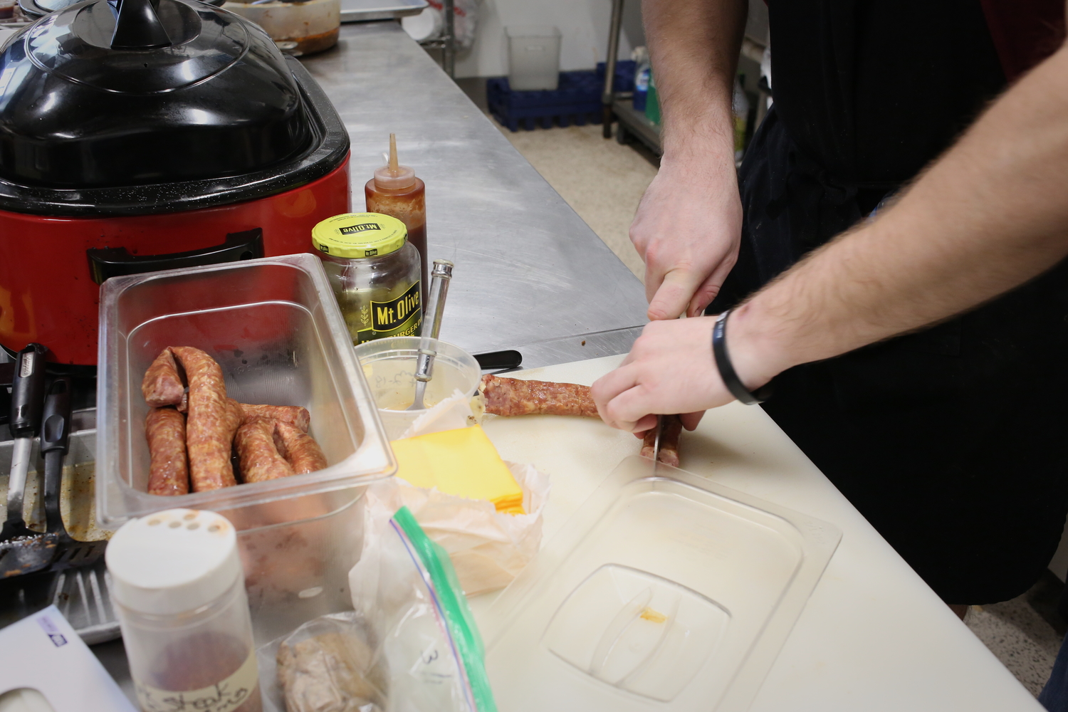 Un cuisinier coupe des saucisses © Globe Reporters