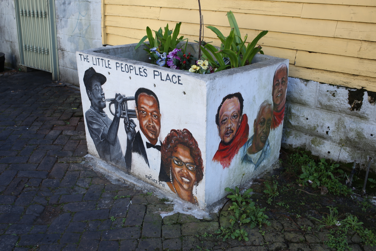 Bac à fleurs à côté du bar, avec des portraits peints de personnalités et musiciens locaux © Globe Reporters